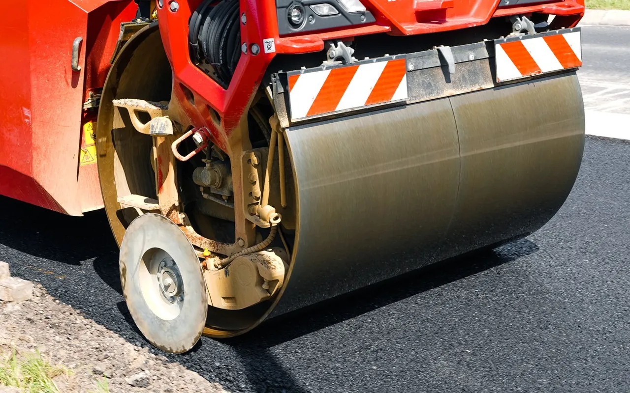 Crew paving an asphalt driveway with a roller in the United States