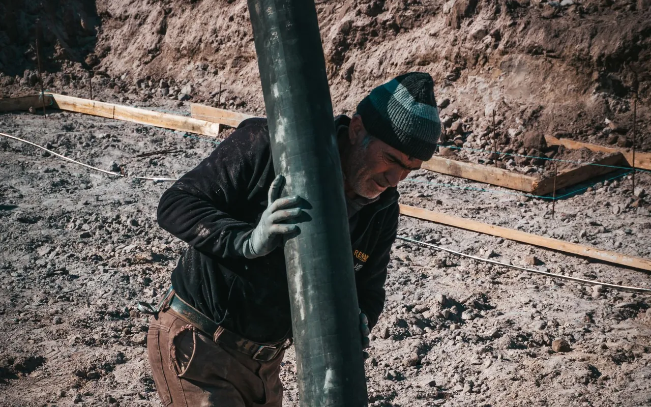 Construction worker pouring a concrete driveway from a chute