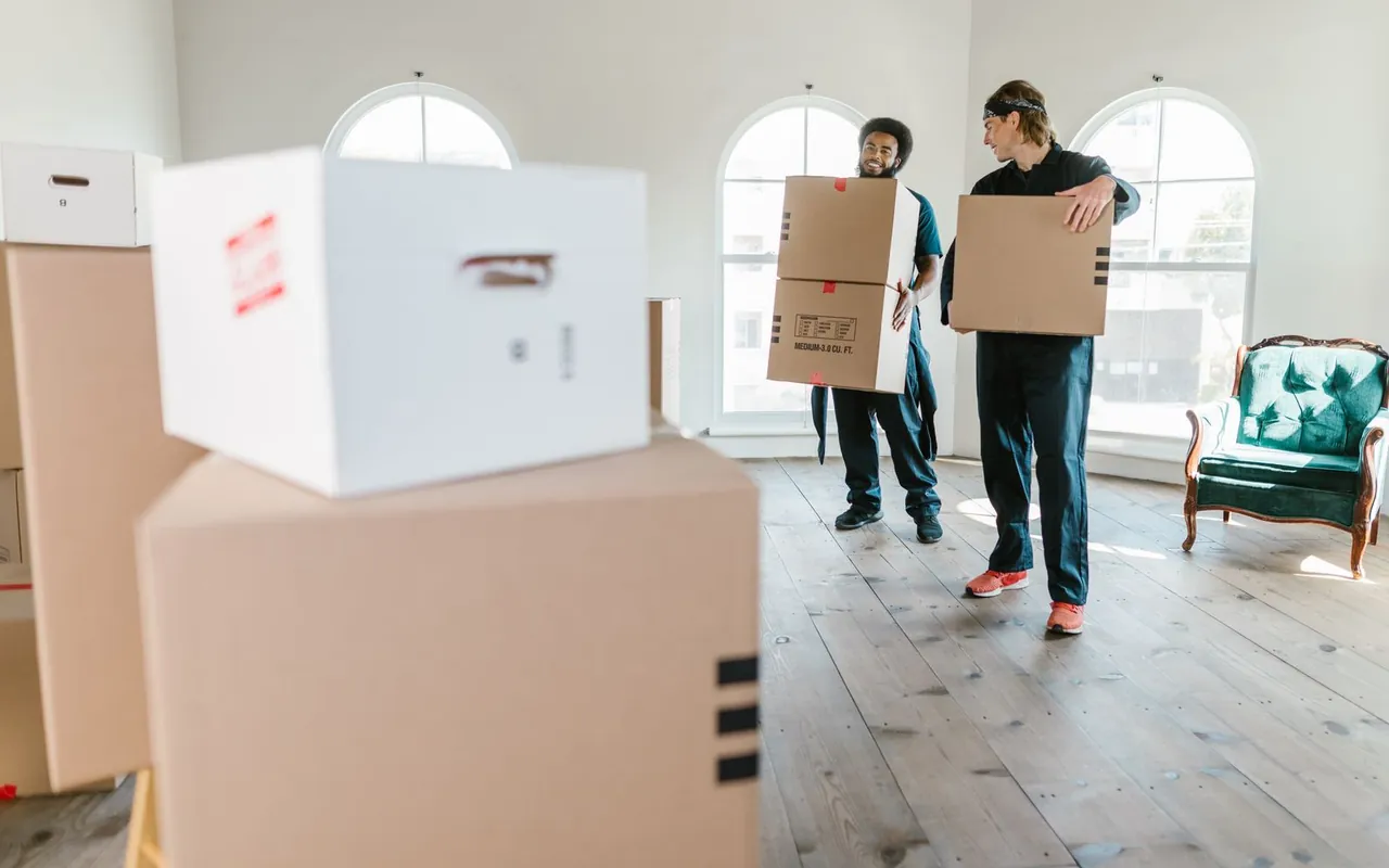 Professional movers carrying boxes into a house